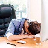 An office employee rests her head on her desk at the office: security awareness